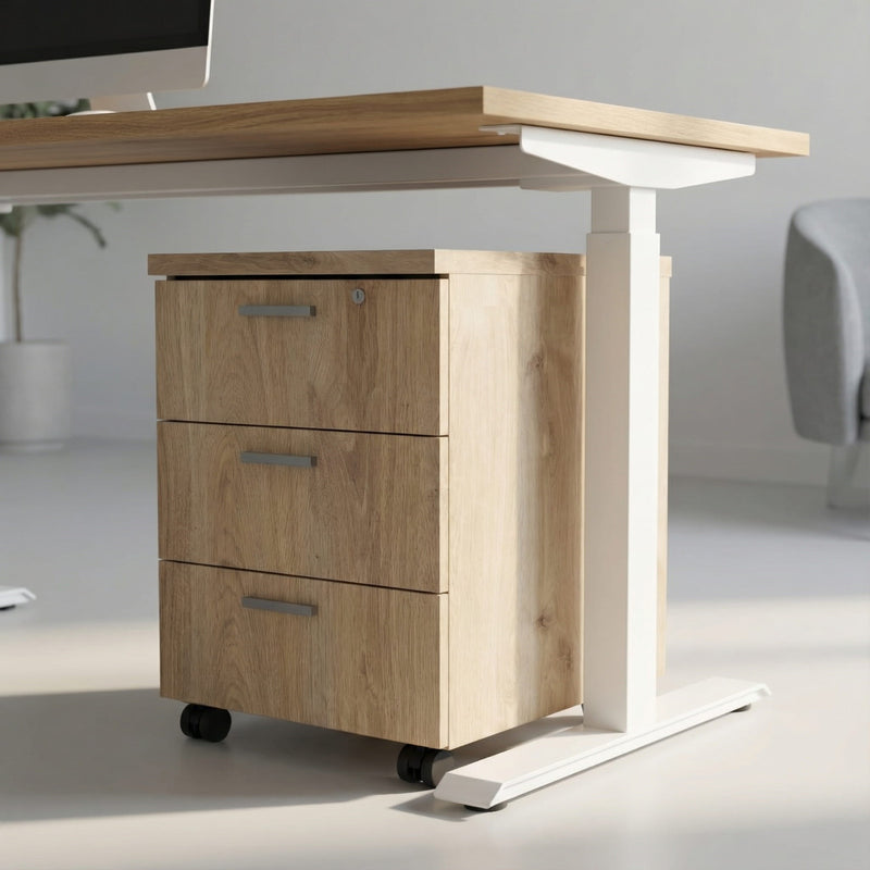 Oak storage with three drawers on wheels under a white framed sit stand height adjustable desk in a modern office room