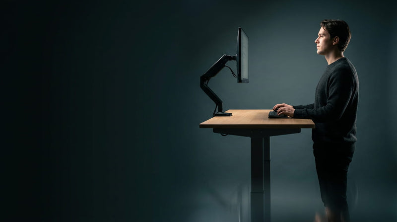 Well-lit home office with a sit-stand desk, an example of good home office lighting