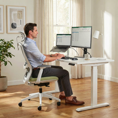 White Man sitting on a ergonomic office chair at a modern office desk with two monitors and a laptop.
