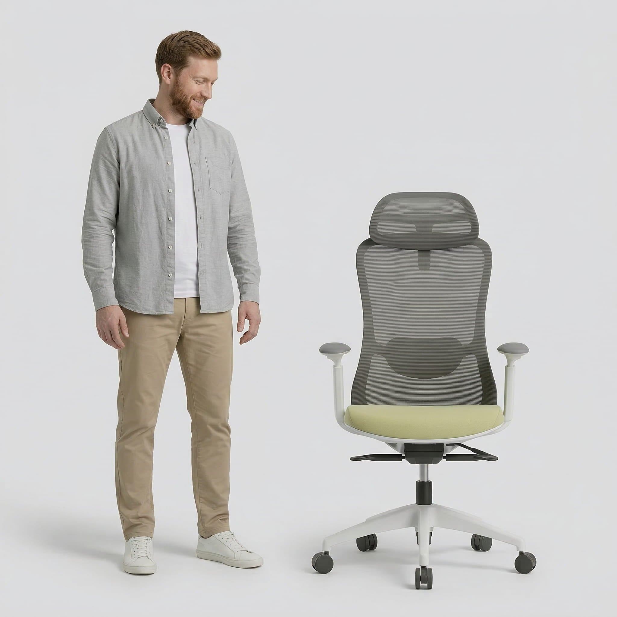 Man standing next to a modern ergonomic with mesh headrest office chair on a white background