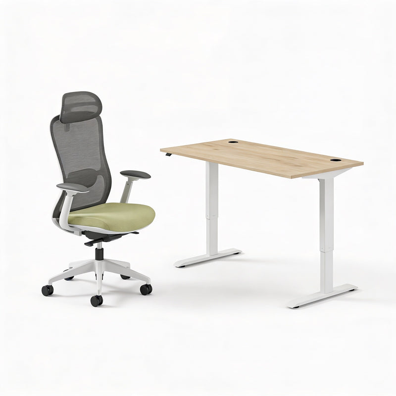 Ergonomic office chair with mesh back and armrests next to a sit stand office desk with a oak top on a white background