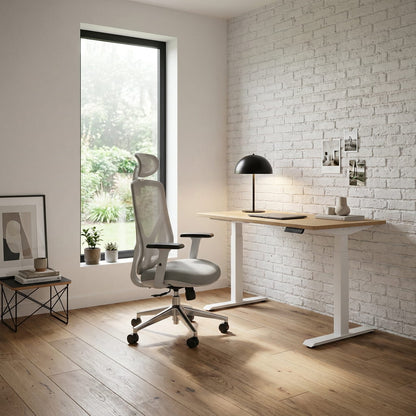 Modern office setup with a desk, chair, and lamp in a room with a white brick wall and large window.