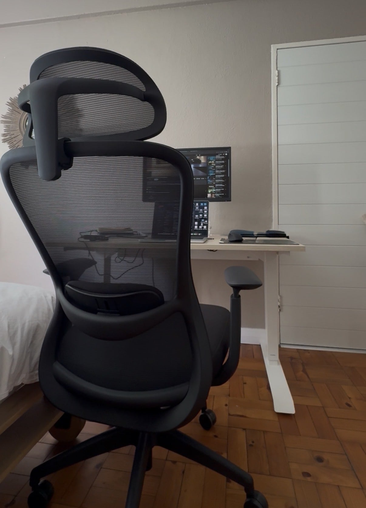 Black office chair in a room with a height adjustable sit stand desk and computer setup.