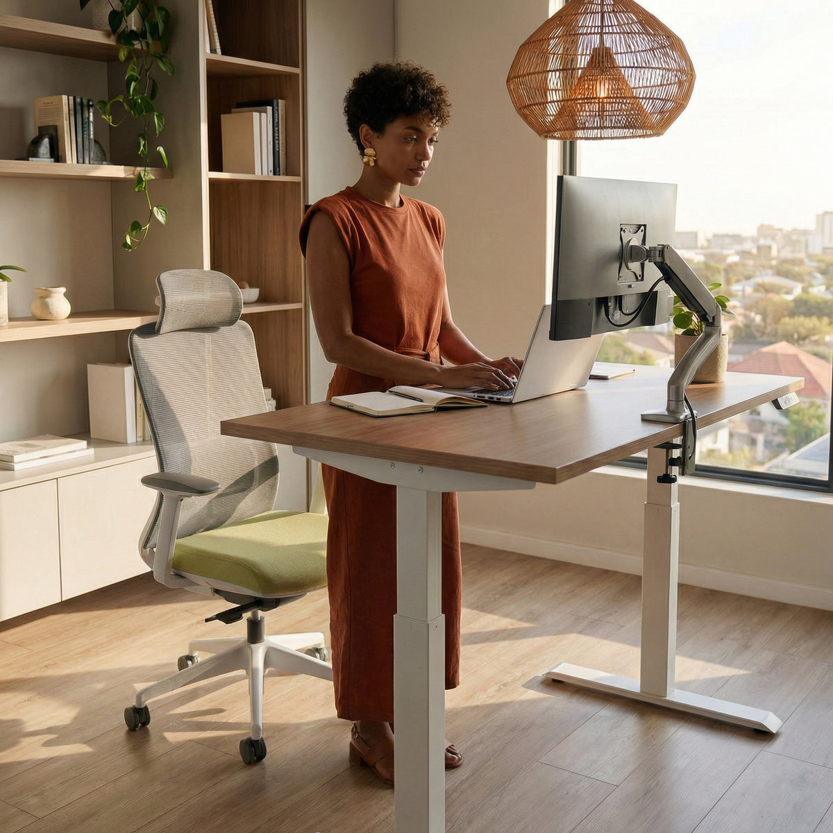 Person working at a standing desk in a home office setting with ergonomic chair behind them