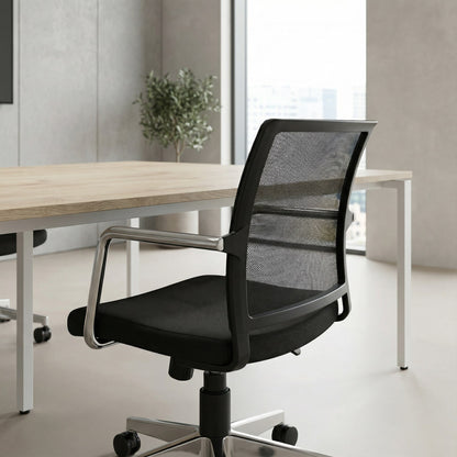 Black office meeting room chair with mesh backrest and a chrome base in an office setting