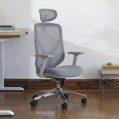 Gray ergonomic office chair with mesh back and headrest in a modern office setting with a height adjustable sit stand desk and books.