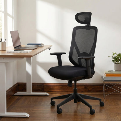 Black ergonomic office chair in a home office setting with a height adjustable sit stand desk and laptop.