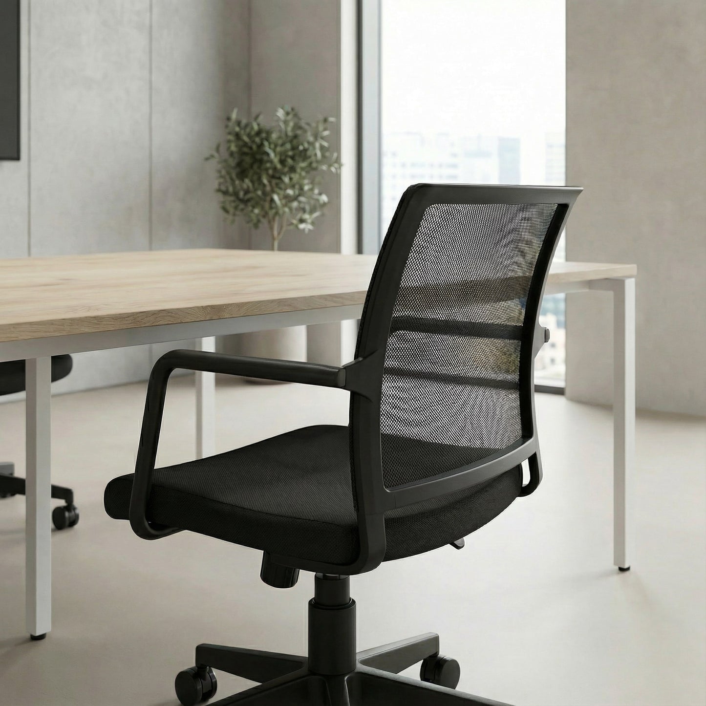 Black office meeting room chair in a modern office setting with a desk and plant.