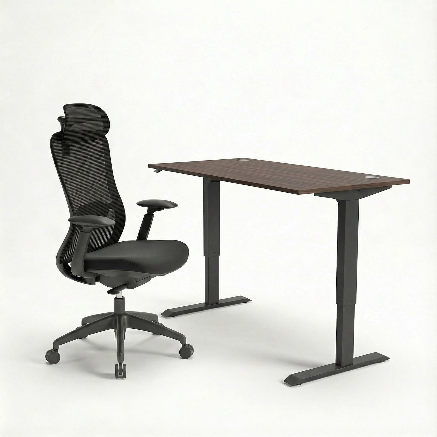 Black ergonomic office chair and adjustable sit stand desk on a white background