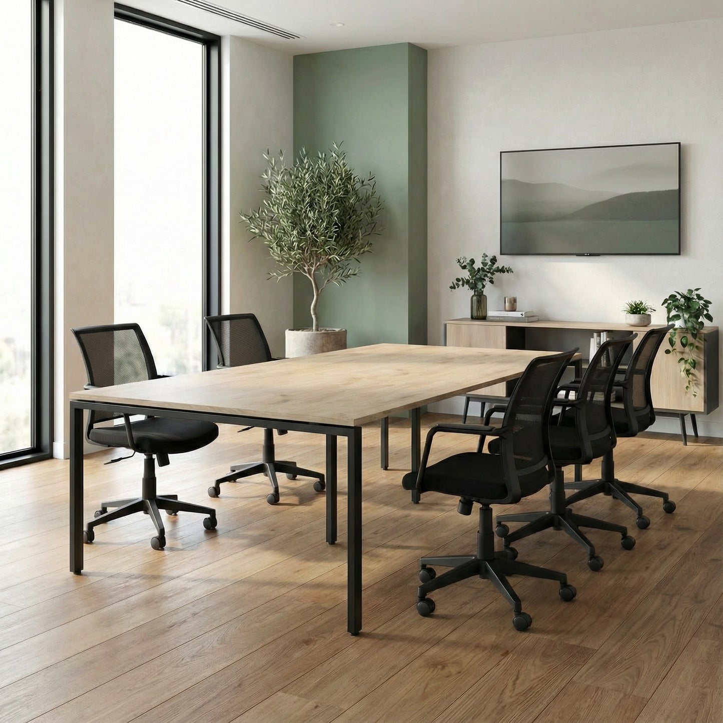 Boardroom space with black boardroom chairs and a meeting table and a plant next to a tv